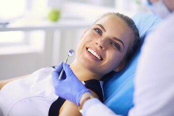 young blond girl smiling sitting in dental chair getting exam, Livonia, MI general dentist